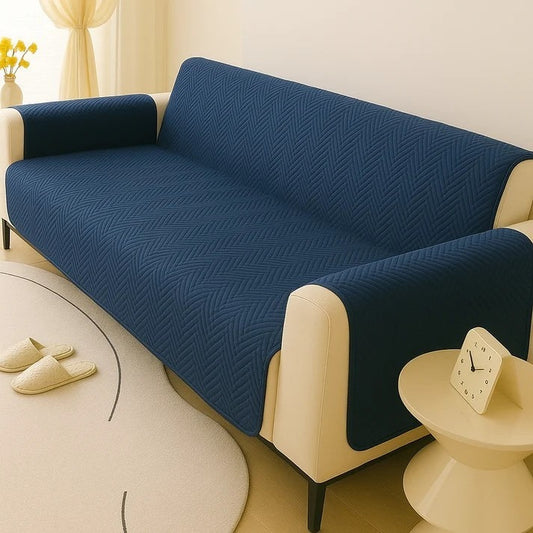 Blue sofa cover on a beige sofa in a living room setting with a clock and slippers visible.