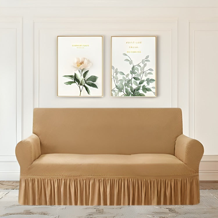 Beige sofa cover on a wooden floor with two framed botanical prints on the wall.
