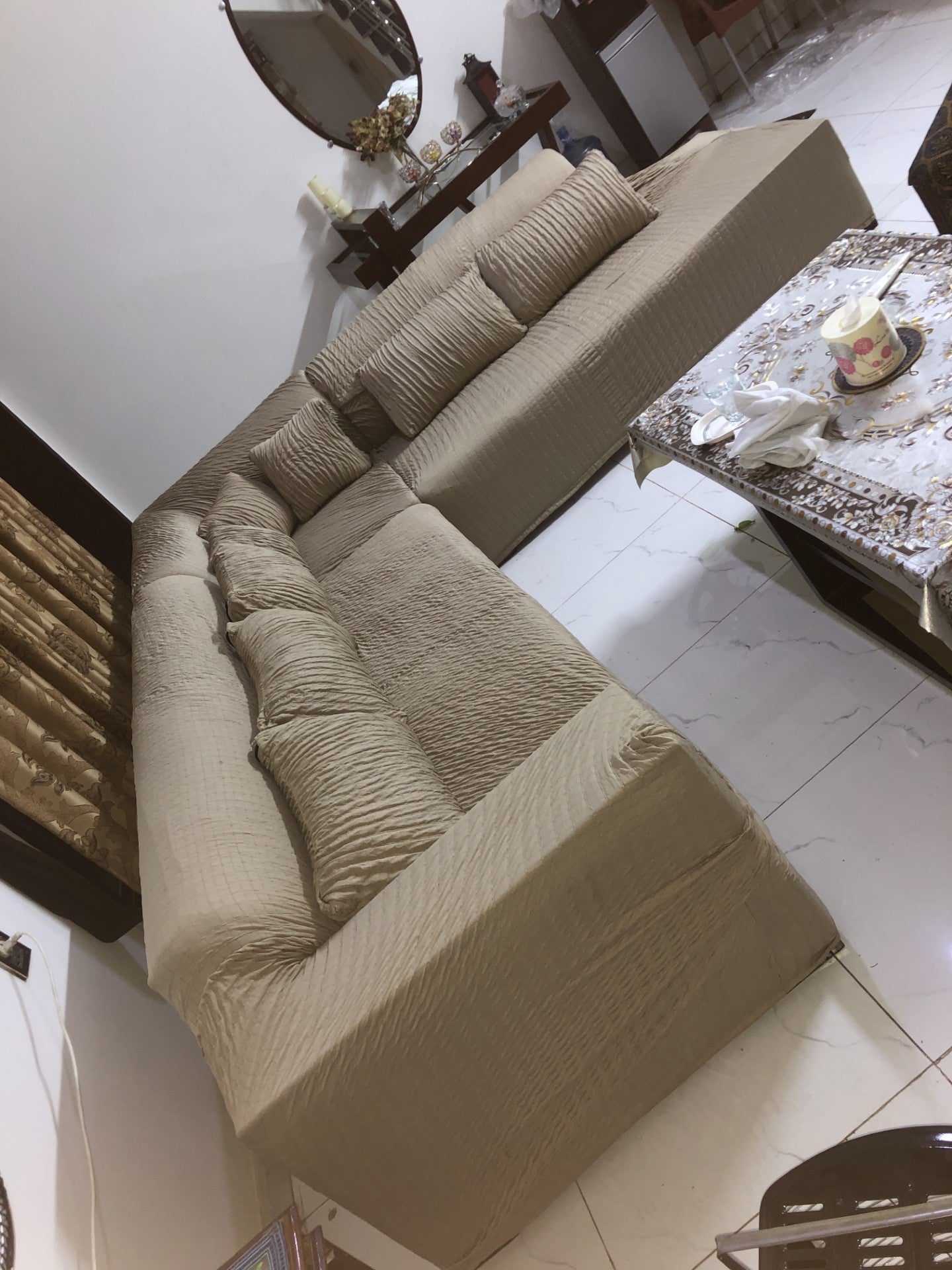 Beige sectional sofa in a living room setting with a table and decor items.