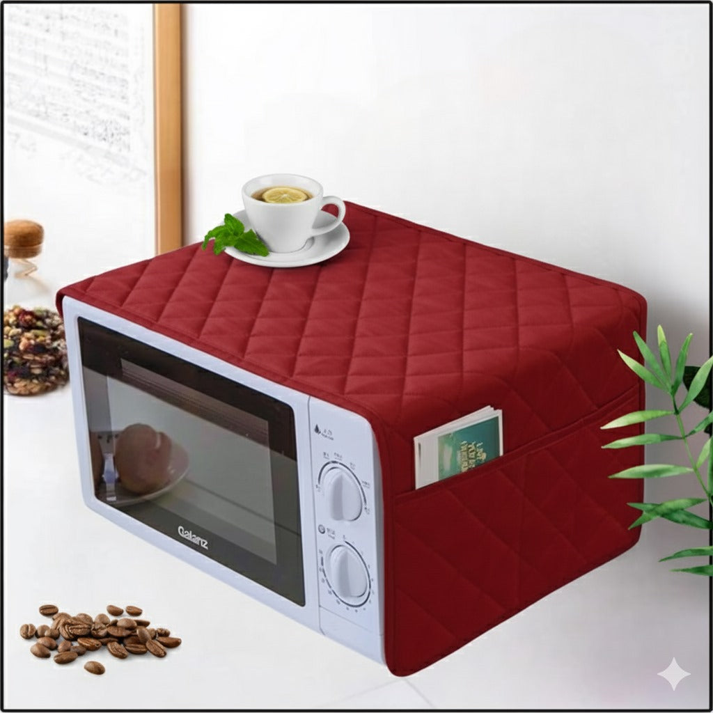 Red quilted microwave cover on a white microwave with a cup of tea and coffee beans on a white surface.