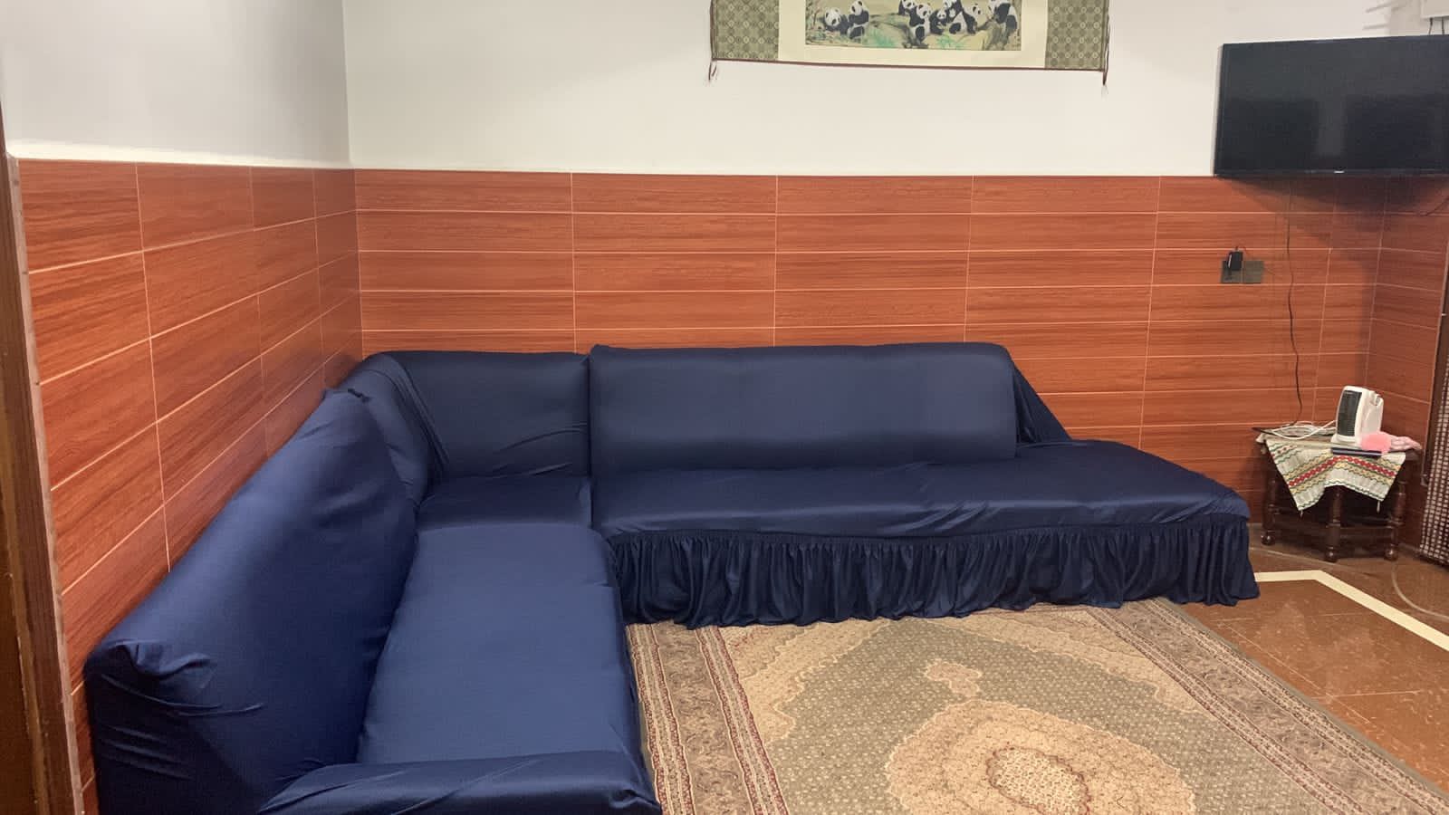 Blue sectional sofa in a room with wooden walls and a TV.
