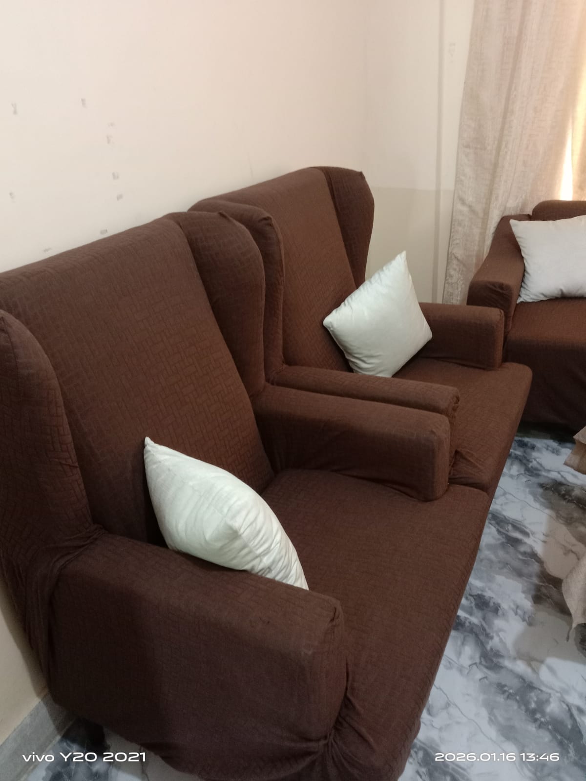Brown sofa with white cushions in a living room setting