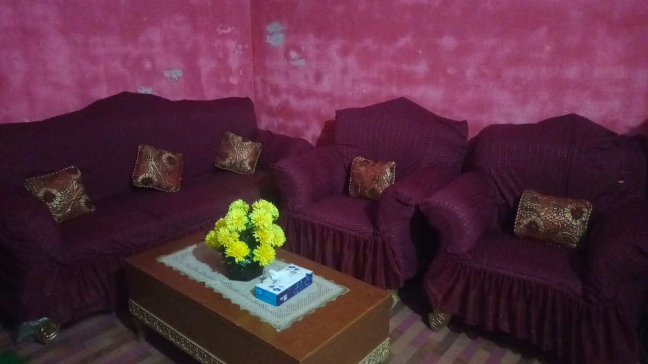 Purple sofa with floral cushions in a room with pink walls and a wooden coffee table.