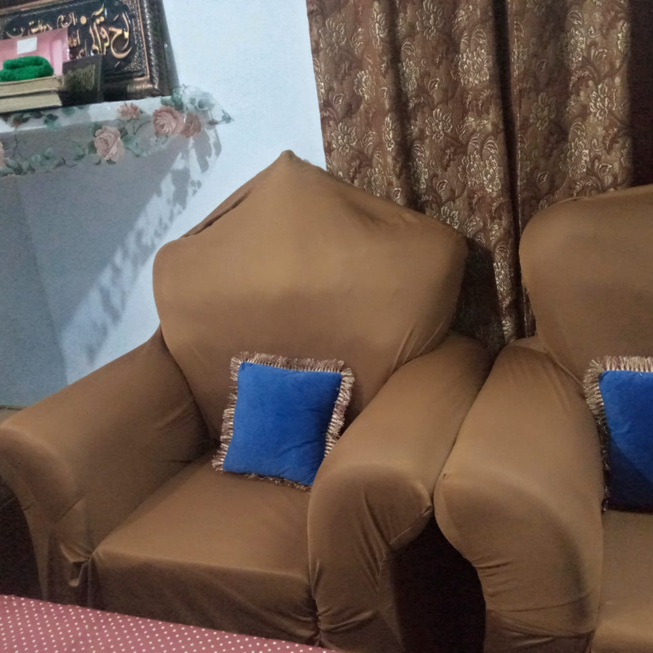Two brown armchairs with blue cushions in a room with a patterned curtain.