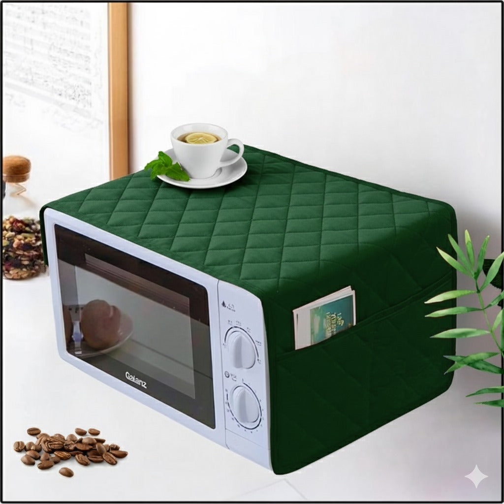 Green quilted microwave cover on a white microwave with a cup of tea and coffee beans on a white surface.