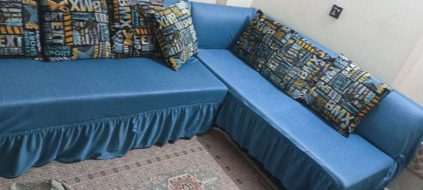 Blue sectional sofa with patterned cushions on a carpeted floor.
