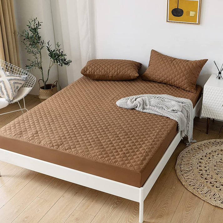 Brown quilted mattress cover on a bed in a room with decor elements.
