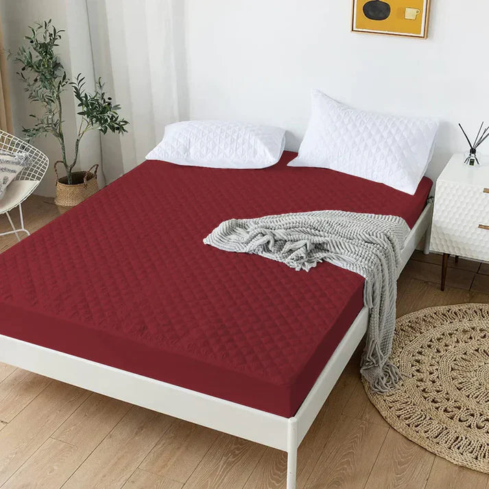 Bed with red mattress cover and gray blanket in a bedroom setting