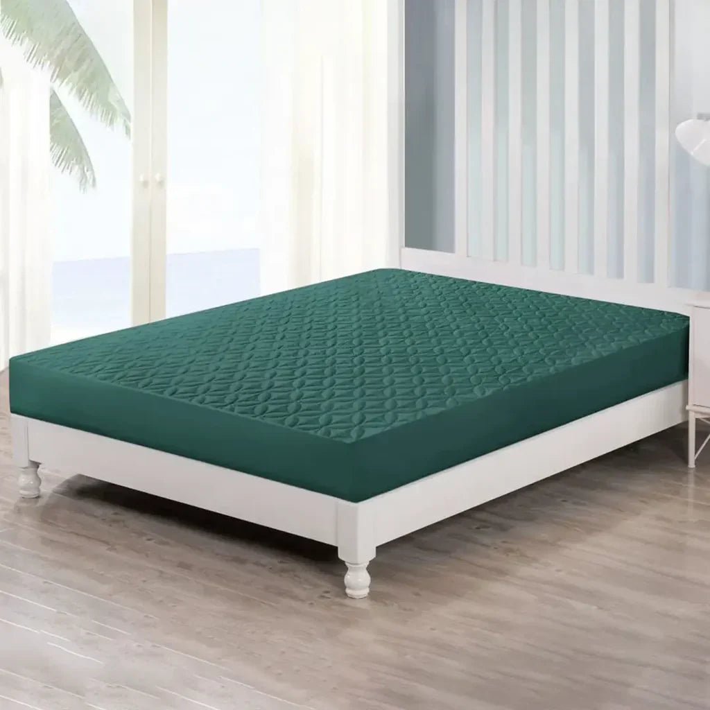 Green mattress cover on a white bed in a room with wooden flooring and white curtains.