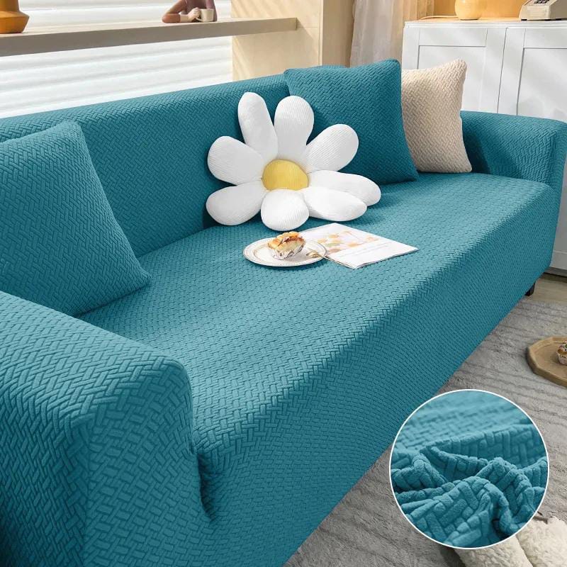 Teal sofa with a decorative pillow shaped like a flower, placed on a light-colored floor.