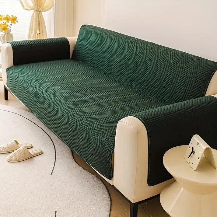 Green patterned sofa cover on a beige sofa in a living room setting.