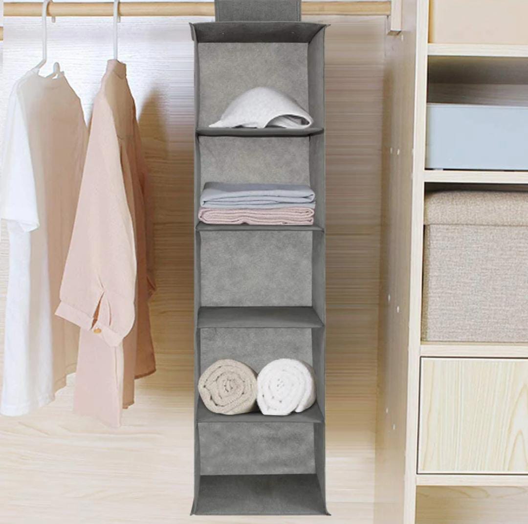 Gray hanging shelf with folded clothes in a closet setting