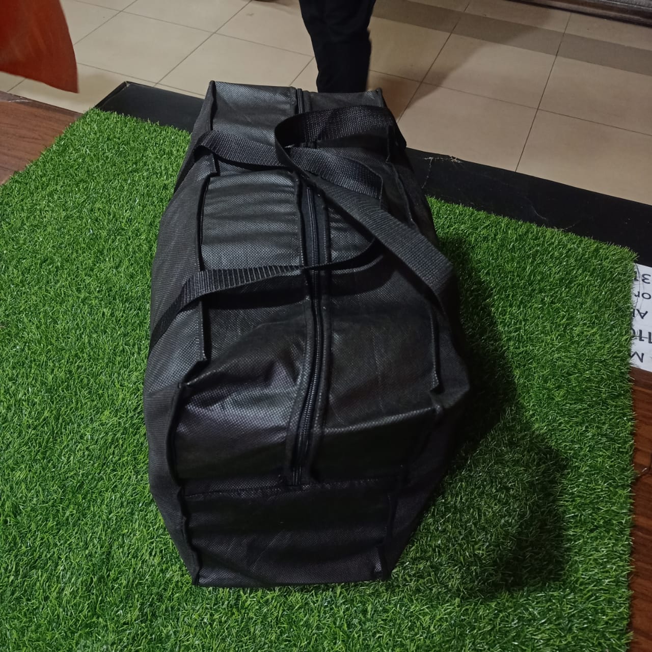 Black duffel bag on a green artificial grass surface