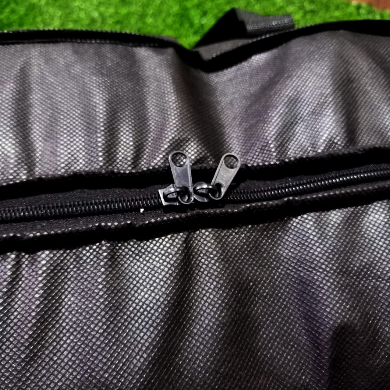 Close-up of a black textured bag with a zipper on a green grass background