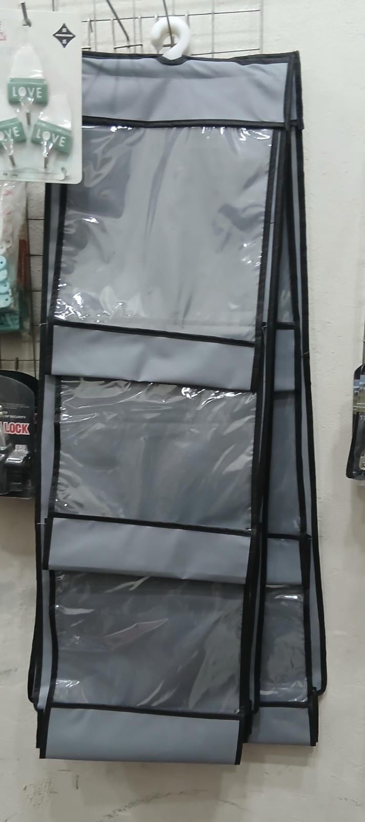 Gray hanging organizer with multiple compartments on a white wall.