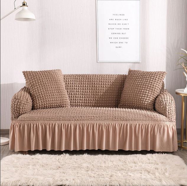 Beige sofa with textured cover in a room with a white wall and framed text art.