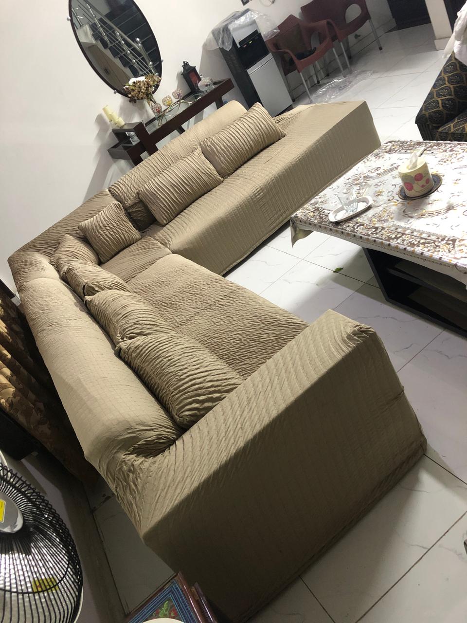 Beige sectional sofa in a living room setting with a marble coffee table and decorative items.
