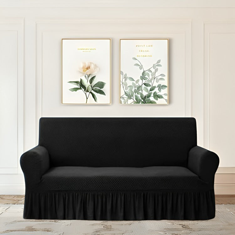 Black sofa cover on a sofa in a living room with decorative wall art.