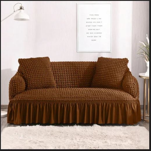 Brown sofa cover on a sofa in a room with a lamp and framed picture on the wall.