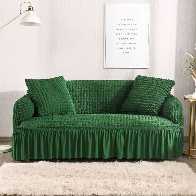 Green sofa with textured cover and matching pillows in a living room setting.