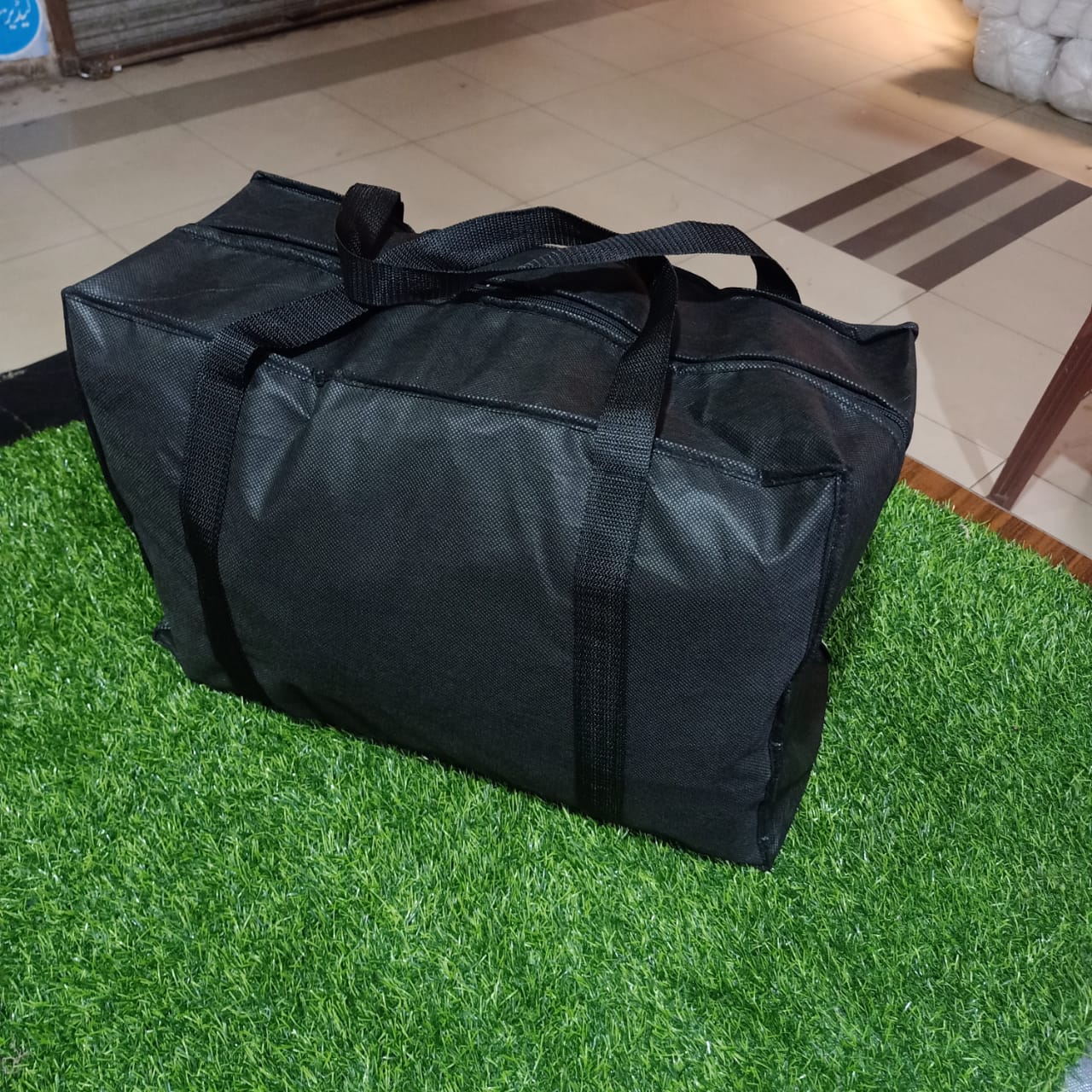 Black duffel bag on a green grassy surface