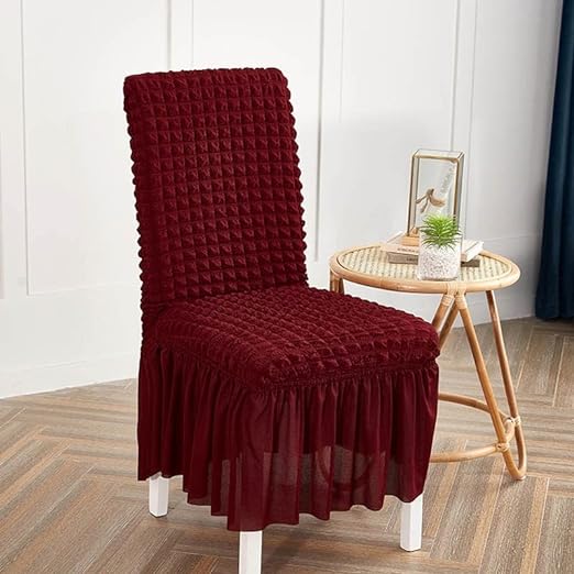 Maroon chair cover on a chair in a room with a small table and decor items.