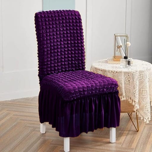 Purple chair cover on a chair in a room with a table and decor.