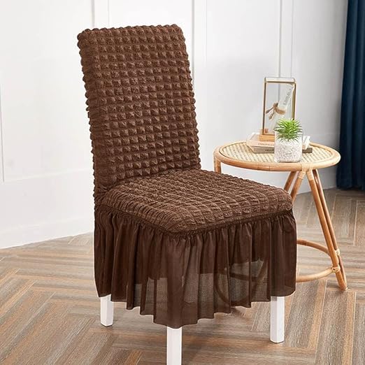 Brown chair cover on a chair in a room with a small table and decor items.
