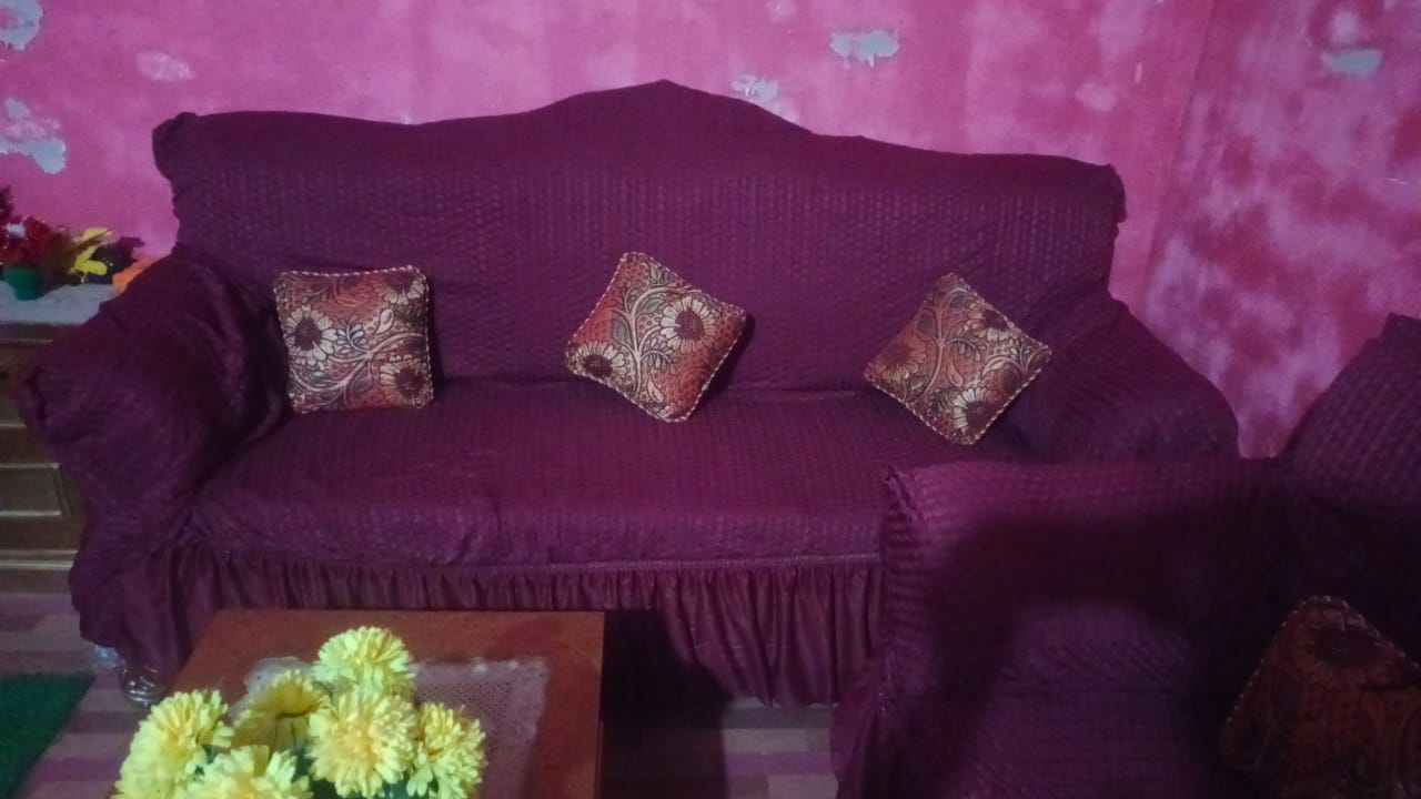 maroon sofa with decorative pillows against a pink floral wallpaper.