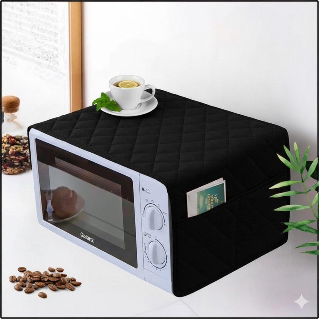Black quilted microwave cover on a white surface with a cup of tea and coffee beans.