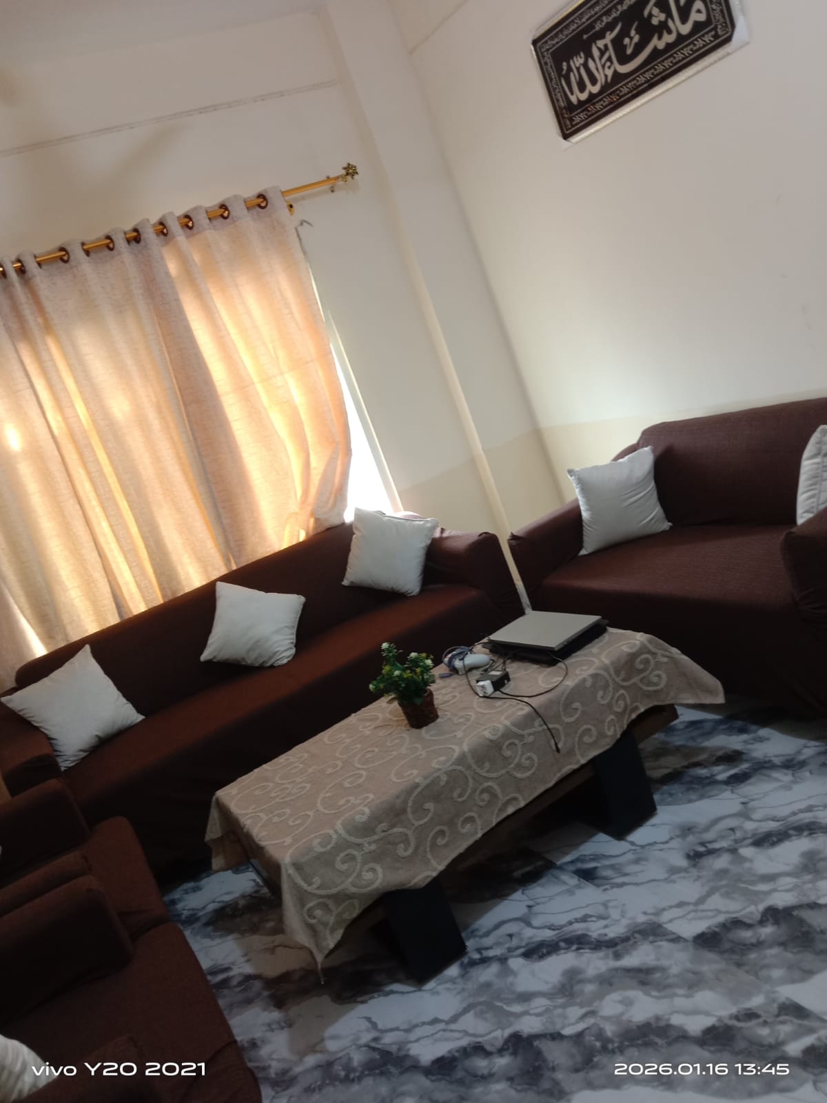 Living room with brown sectional sofa, white cushions, and a small table with decor items.