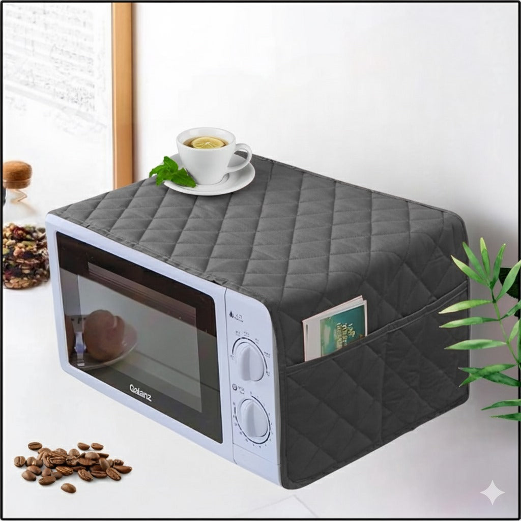 Gray quilted microwave cover on a white microwave with a cup of tea and coffee beans on a white surface.