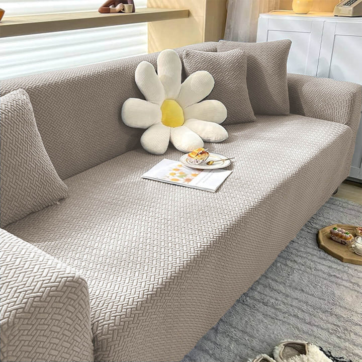 Gray sofa with a decorative pillow shaped like a flower in a living room setting.